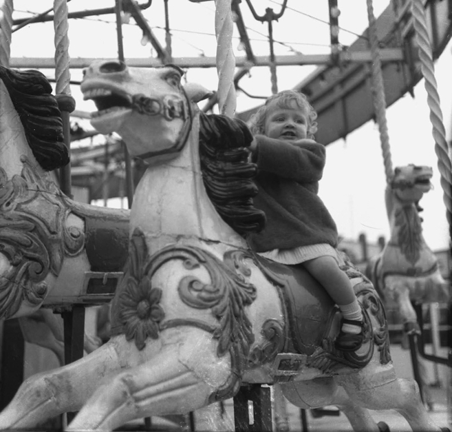 2.12 1950s, girl on a carousel ride at a fairground, England, UK